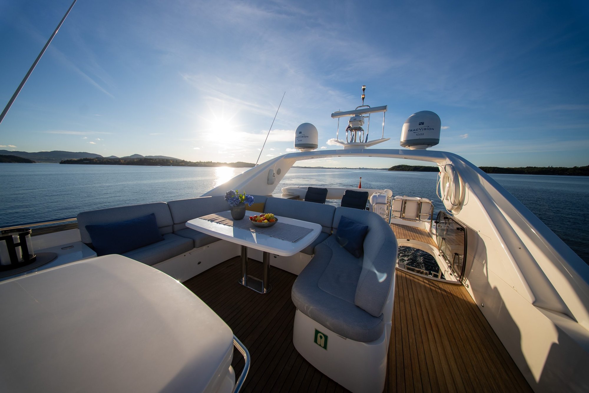 The flybridge of Barolo III with seating and a table, low sun over the islands